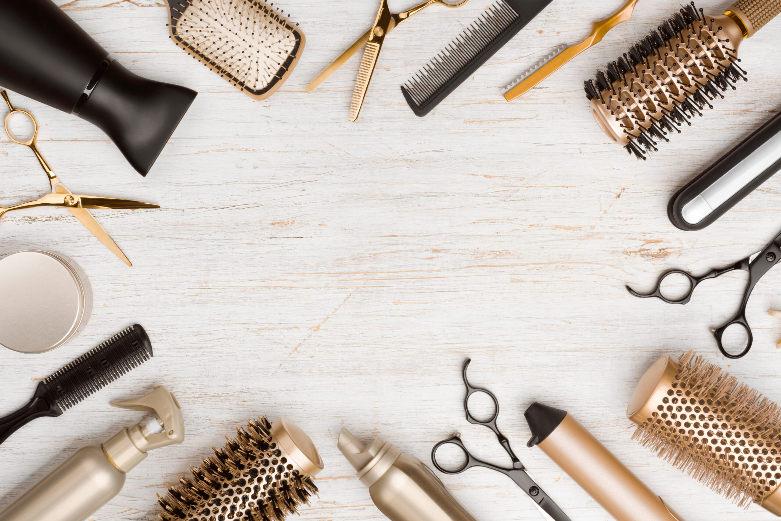 A shot from above of various golden-colored hairstyling tools resting on a table in a circular shape